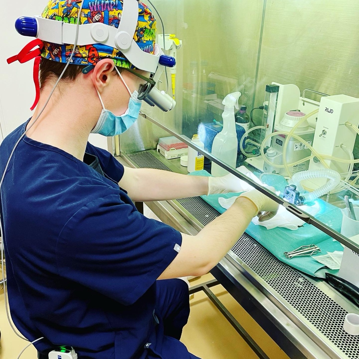 Dimitrios Magouliotis conducting laboratory research using microsurgical equipment.