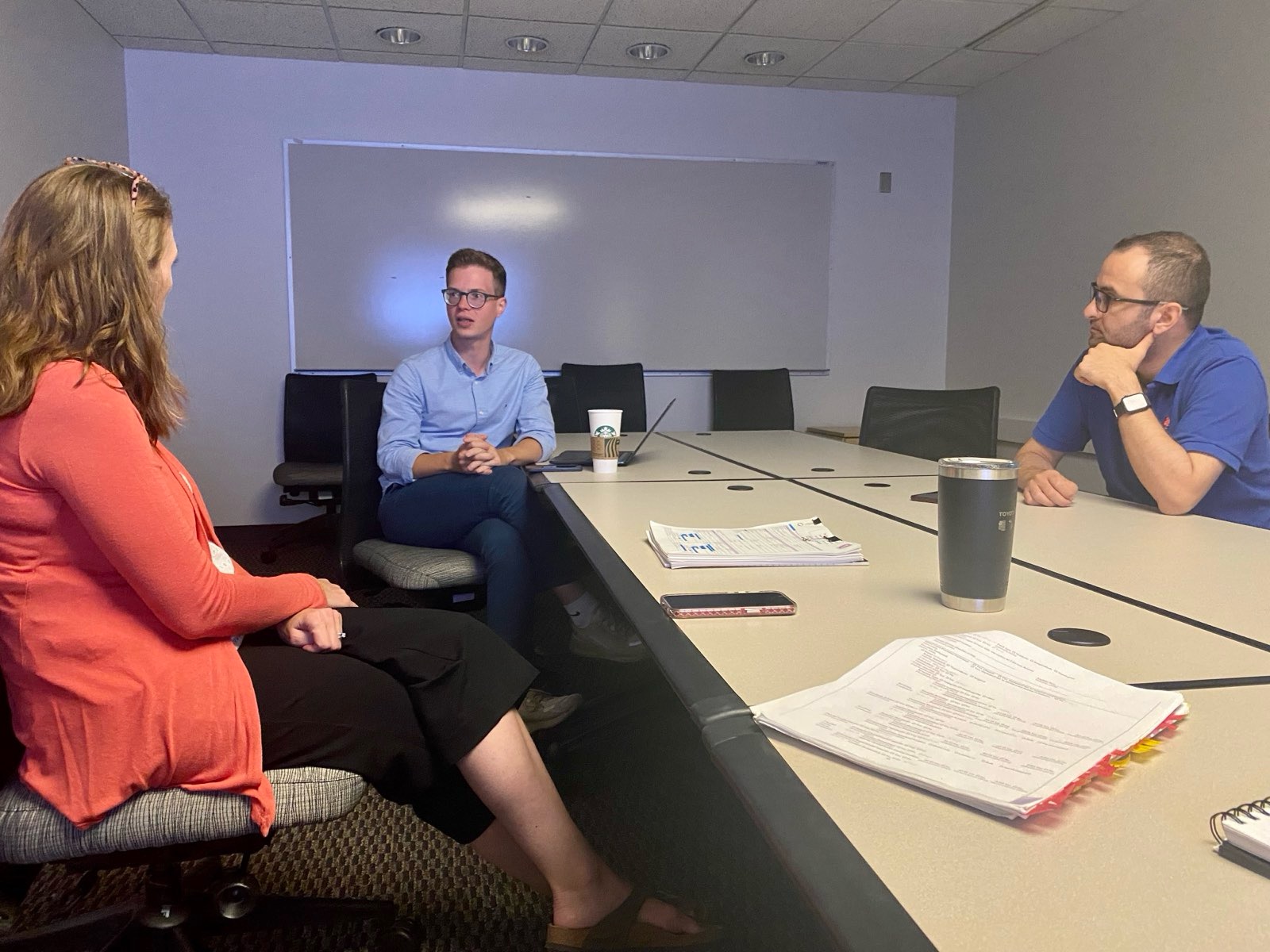 Dimitrios Magouliotis in discussion with two colleagues around a meeting-room table.